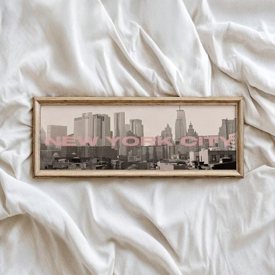 close-up artwork detail of Panoramic framed wall art showing a black and white New York City skyline photo with blush pink NEW YORK CITY typography and modern travel poster style.
