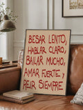 Cream canvas with red Spanish quote lettering shown beside a leather sofa