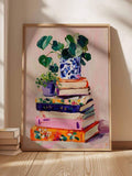 Colorful stacked books and plants canvas leaning in pale wood frame