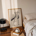 Minimal crane line art poster beside bed with coffee tray and black lamp