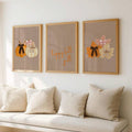 Autumn canvas poster trio in warm frames above a cream bench with sunlight reflections