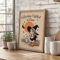 Wood framed retro Halloween witch poster on kitchen counter with mugs and plant