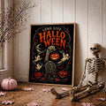 Framed cemetery Halloween poster beside seated skeleton pumpkins ghosts and bats