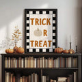 Black framed Trick Or Treat Halloween poster on bookshelf mantel with pumpkins candles dried flowers and checker border