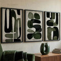 Black-framed olive abstract triptych over a walnut console