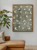 Framed white seabird print above a leather chaise beside a leafy plant