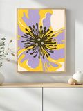 Purple and yellow abstract flower wall art in a natural wood-look frame above a white cabinet