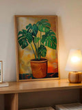 Framed tropical plant artwork displayed on a wood console with table lamp