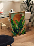 Tropical green leaf print leaning beside a glass desk in a bright room