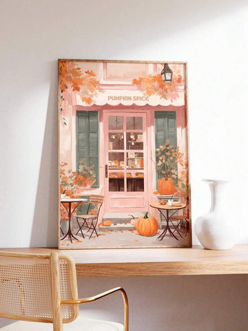 Framed pink pumpkin spice cafe autumn print on wooden desk beside white vase and cane chair