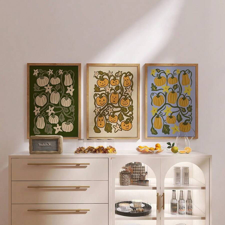 Three pumpkin canvas posters over white sideboard