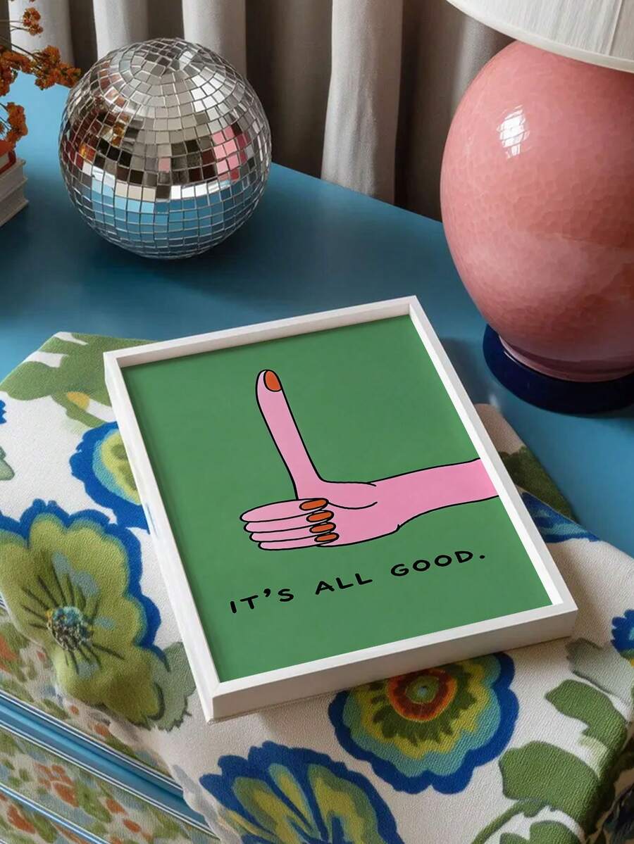 White framed It's All Good hand gesture print beside a disco ball and pink lamp