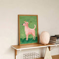Framed folk art dog poster on modern shelf with lamp books and wire basket
