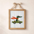 Ribbon-hung wooden frame showing a scarfed crocodile in a convertible
