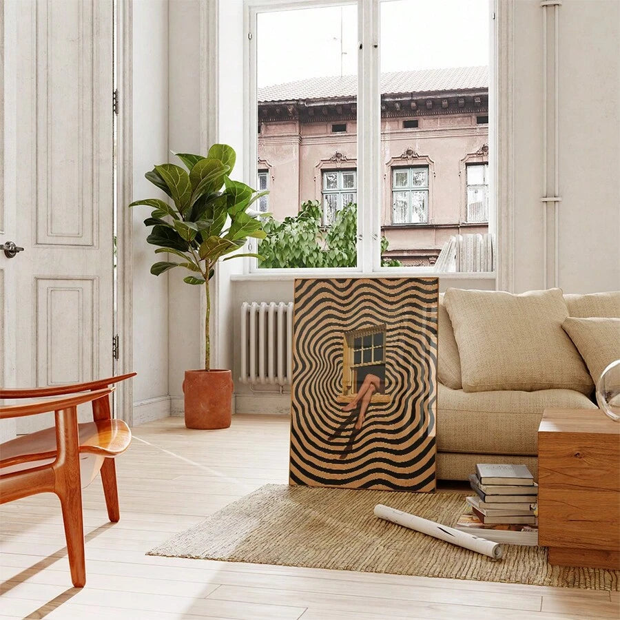 Black-and-tan surreal window print leaning beside cream sofa in bright neutral living room