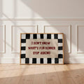 Framed kitchen quote poster centered against white paneled wall with sunlight across wood floor