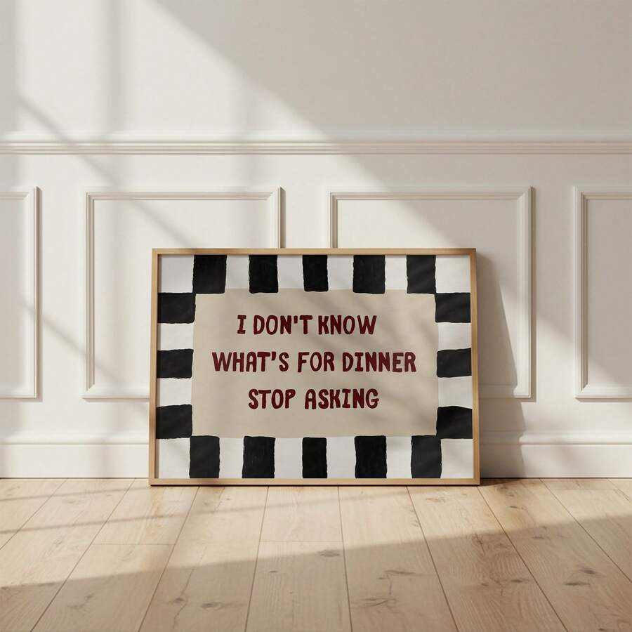 Framed kitchen quote poster centered against white paneled wall with sunlight across wood floor