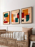 Three framed mid century geometric posters above wooden crib in nursery