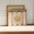 Unframed maple leaf canvas art leaning against wood supports