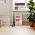 Small framed high class joint typography print below window beside magazines and green plants
