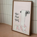 Funny toilet paper quote art leaning against tiled bathroom wall