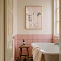 Go Piss Girl canvas displayed above pink tiled bathtub
