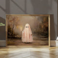 Gold framed pink ghost canvas leaning on a wooden floor in a softly lit room