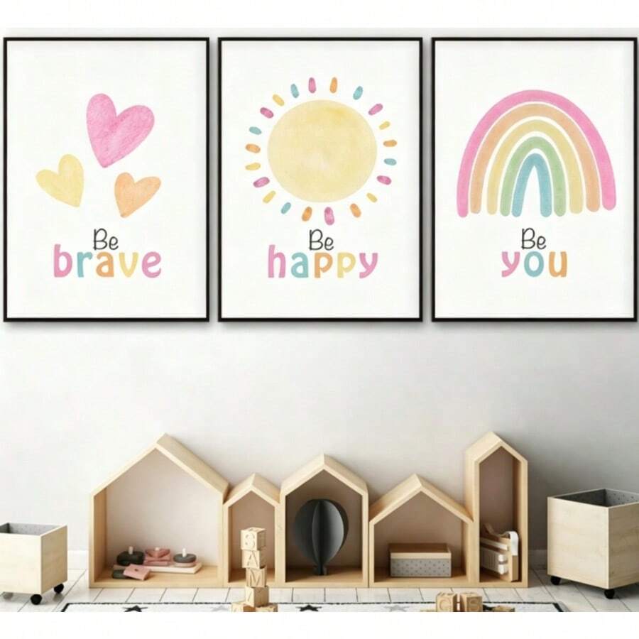 Black-framed nursery prints above toy shelves with Be brave hearts, Be happy sun and Be you rainbow
