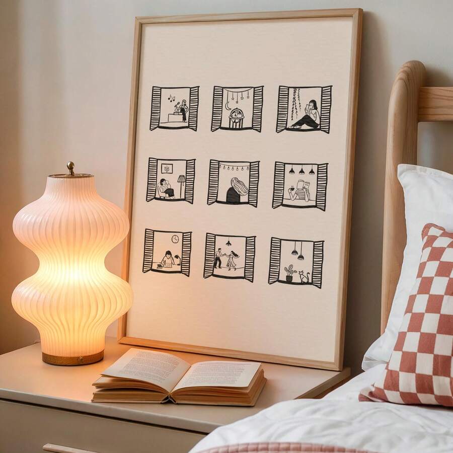 Nine-window line-art print beside a glowing lamp, bed, and open book
