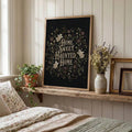 Wood framed haunted home floral print leaning on a rustic bedroom shelf