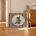 Modern Halloween witch wall art in a light wood frame beside a wooden dresser