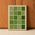 Light wood framed green tile artwork leaning against a wood-paneled wall