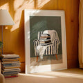 White-framed armchair-and-books artwork in sunlit wood-paneled room beside stacked books