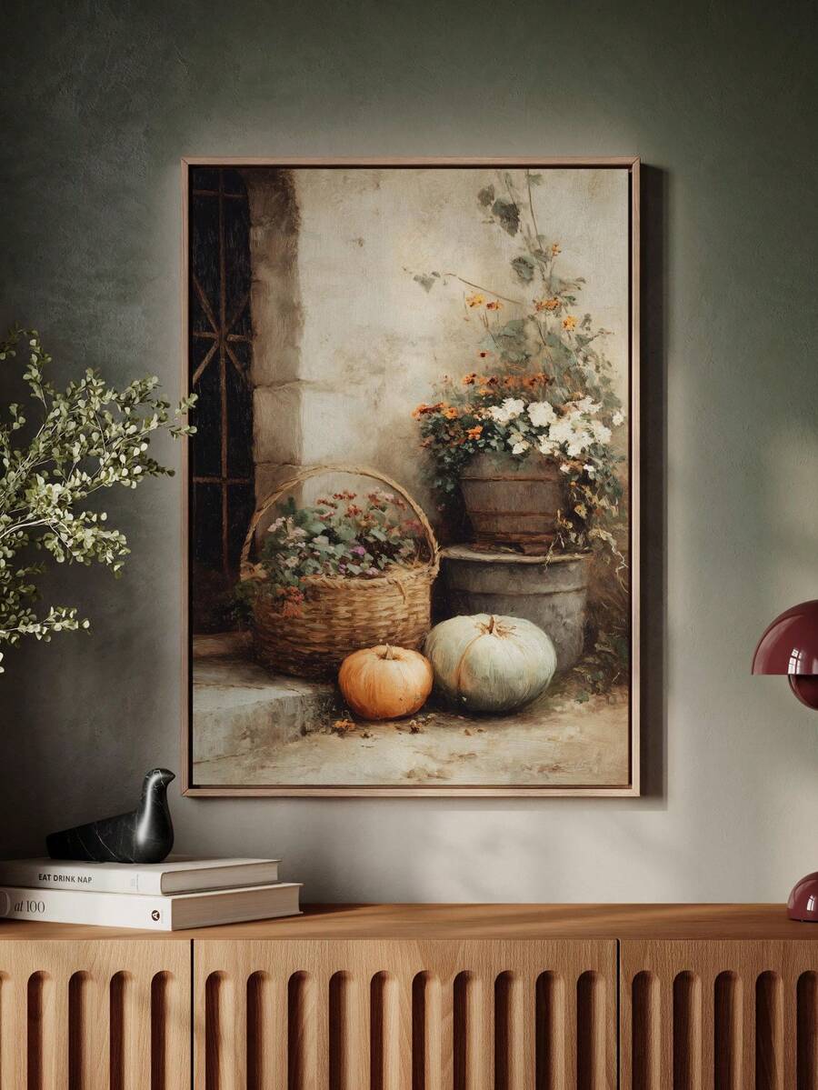 Large framed pumpkin and flower still life leaning on a sunlit cream wall