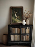 Realistic stag artwork above a mantel with books and candles