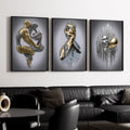 Three black-framed metallic-effect figure artworks above black sectional in modern living room