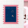 Vertical navy quote print with floating woman in a pink scalloped frame on a tiled wall
