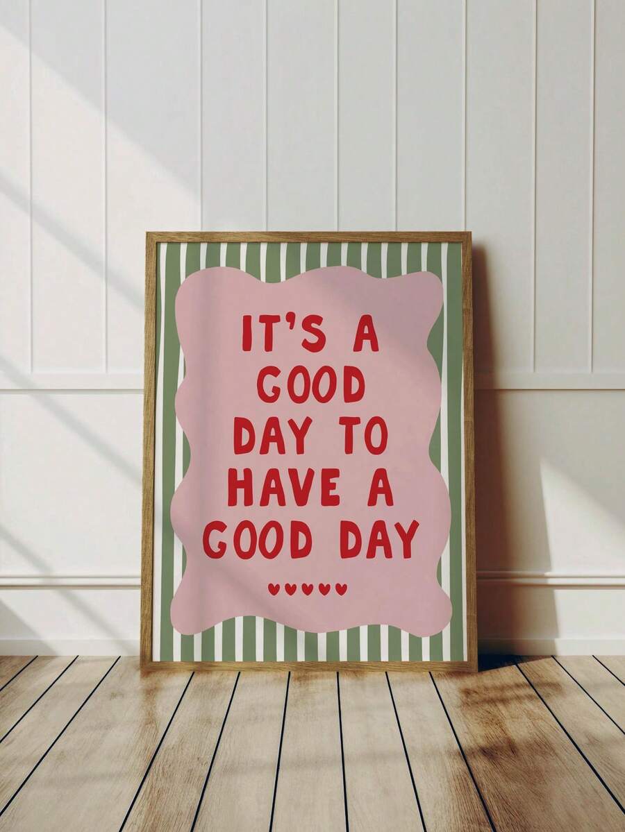 Framed good day quote print leaning against a white paneled wall on a wood floor