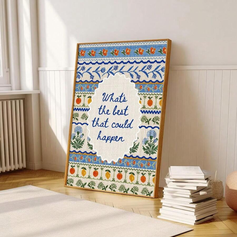 Folk embroidery quote artwork leaning beside books in sunlit room