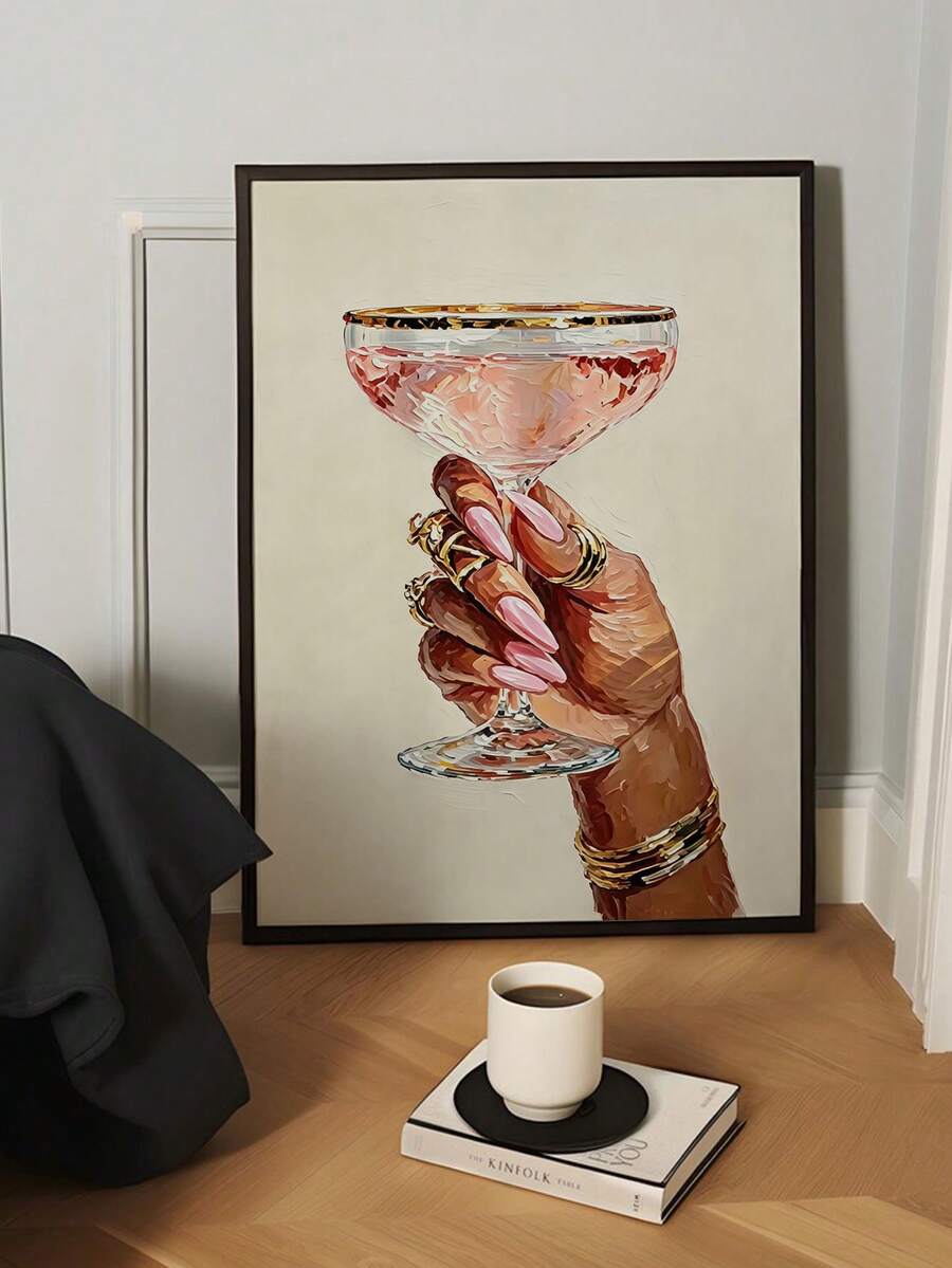 Pale-framed jeweled hand artwork with pink coupe drink beside a bright window