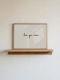 Minimalist love you more canvas poster resting on natural wood shelf