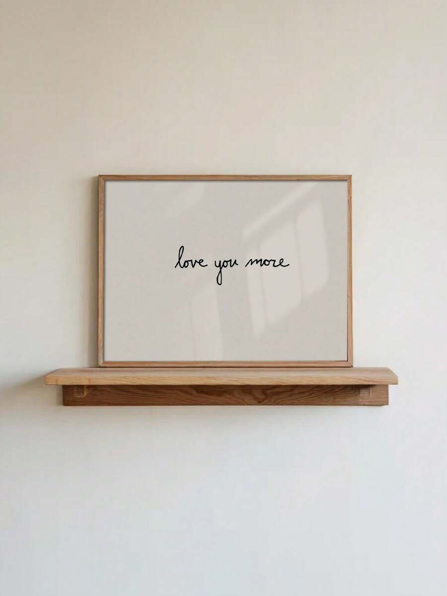 Minimalist love you more canvas poster resting on natural wood shelf