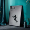 Grayscale basketball dunk silhouette print in a black frame displayed on a teal room floor
