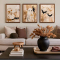 Framed pumpkin ghost and bat paintings above a beige sofa