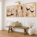 Gold-framed pumpkin ghost and bat prints above a wooden entry bench