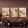Framed pumpkin ghost and bat art over a candlelit Halloween table