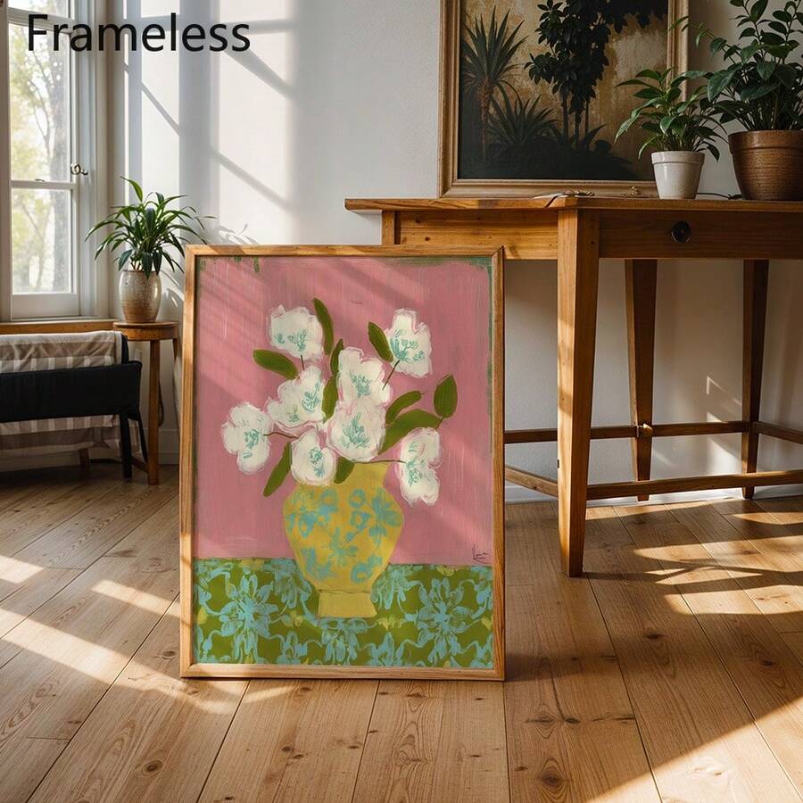 Framed flower vase canvas in bright room beside wood table and houseplants