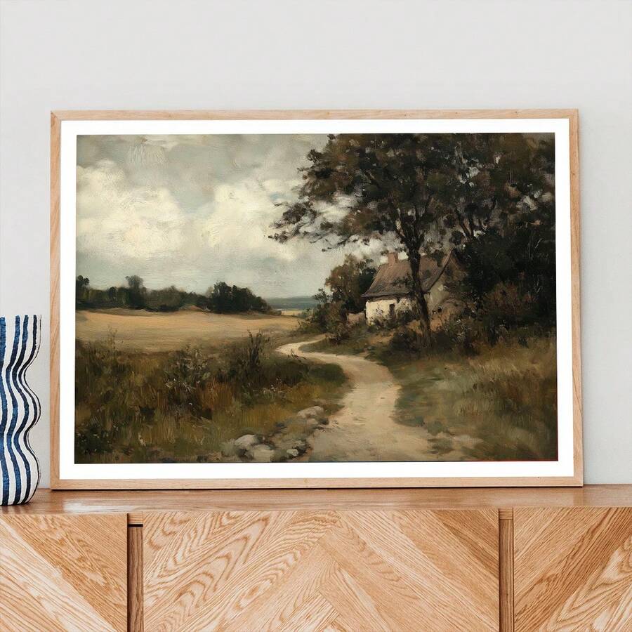 Matted cottage landscape above a wooden sideboard