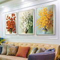 Three floral bouquet canvases arranged over a sofa in a modern living room