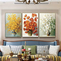 Three vase flower posters above a blue sofa in a bright sitting room
